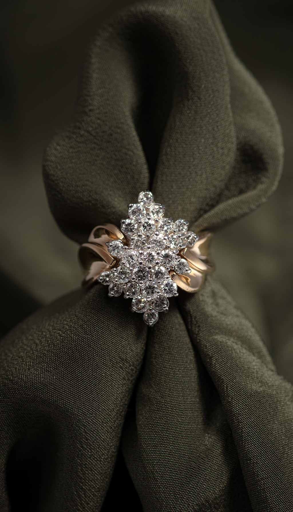 Diamond cluster ring on a green fabric background