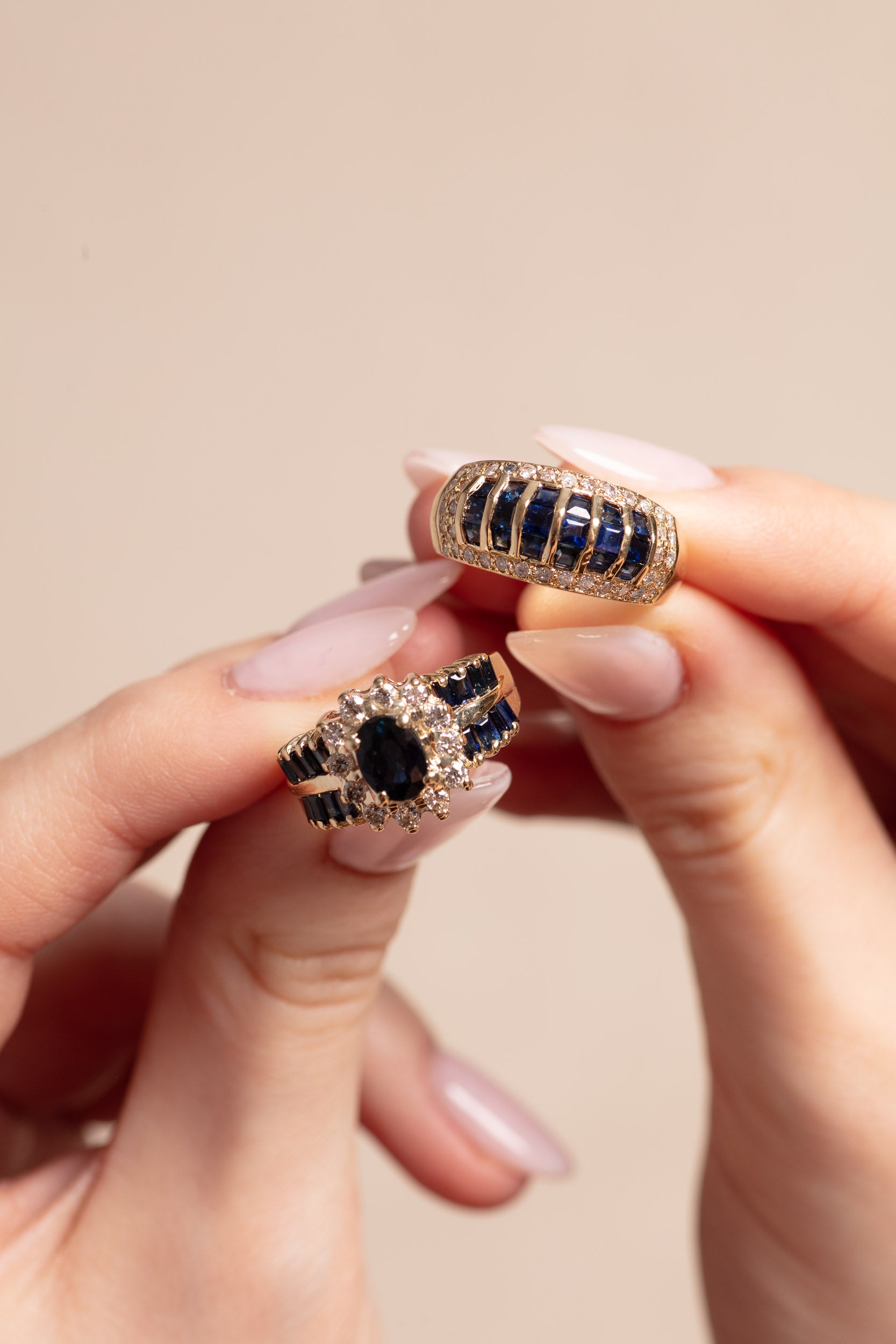 Two sapphire gold rings held in hands